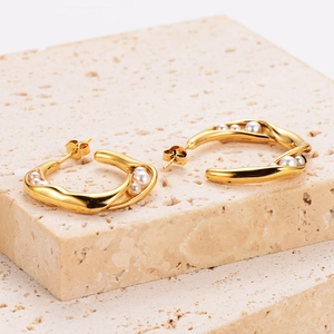 Golden C-shaped twisted metal hoop earrings with elegant white pearls on stone base