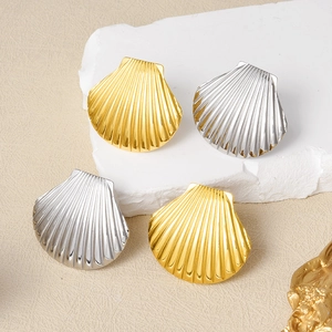 Detailed close-up of gold and silver seashell rings on white stone and beige surface