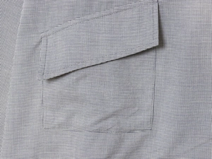 Detailed close-up of a grey houndstooth shirt pocket with a classic flap design