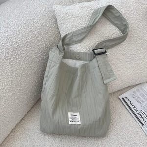 Detail of sage green pleated canvas tote showing textured fabric and brand label