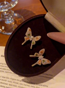 Detailed close-up of zircon bow-knot earrings with colorful gems in a velvet jewelry box