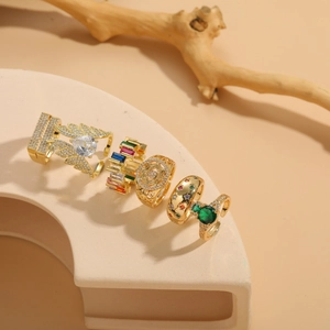 Detailed set of 14K gold-plated rings with colorful stones on beige display