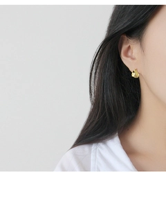 Gros plan d'une femme portant des boucles d'oreilles géométriques en argent fin 925 doré