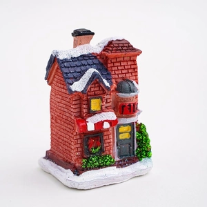 Lighted Christmas resin house ornament with snow-capped roofs and green trees
