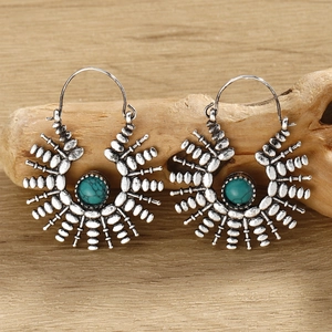 Close-up of silver tribal hoop earrings with turquoise stones on a rustic wood background