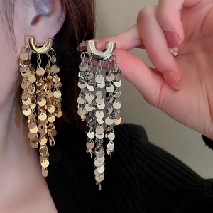 Detailed view of U-shaped tassel earrings featuring shiny metal sequins in gold and silver