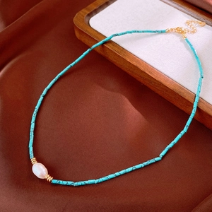 Close-up of aquamarine beaded necklace with a natural white pearl and gold clasp details