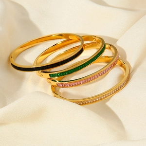 Stack of 18k gold plated stainless steel bangles with colorful zircon stones on silk fabric