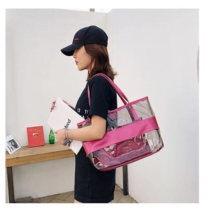 Detail of transparent PVC tote bag with rose red leather trim shown on model