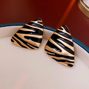 Macro shot of vintage gold-plated triangle earrings with black enamel in a jewelry box