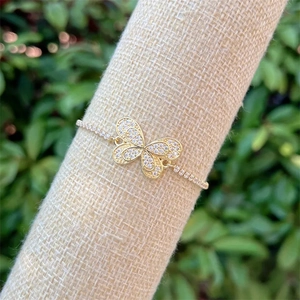 Macro shot of 18k gold-plated butterfly bracelet with colorful zircon stones on a linen stand