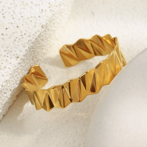 Détail d'un bracelet doré 18K avec motifs géométriques sur support en pierre