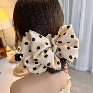 Detailed back view of a large beige polka dot bow hair clip worn on a low ponytail