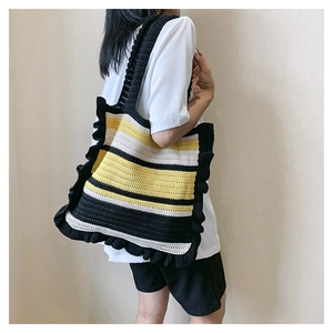Detail of handmade knit tote bag with color block stripes and ruffled edge on model