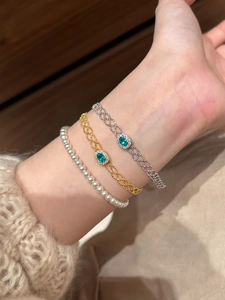 Stacked vintage gold and silver woven bracelets with green oval gemstones and pearls