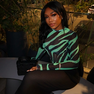 Detail of green and black zebra print mesh long sleeve top styled with a quilted handbag