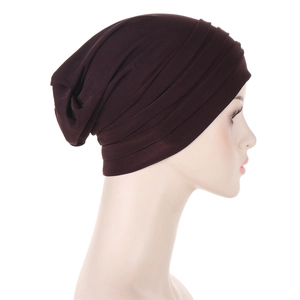 Detail of dark brown pleated turban headwrap on a white mannequin head display