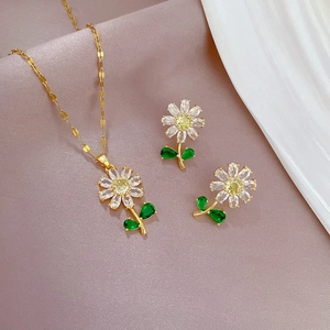 Detailed view of floral titanium jewelry set with green and yellow stones on purple velvet