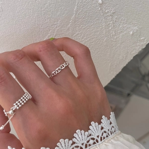 Detailed view of silver-plated chain rings and beaded band on hand with lace sleeve
