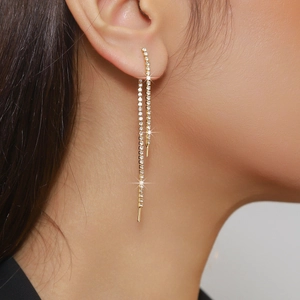 Close-up of elegant gold long fringe earrings with pavé rhinestones on model's ear