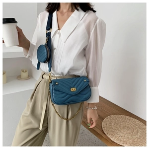 Blue quilted crossbody bag with small round pouch shown on a casual female model