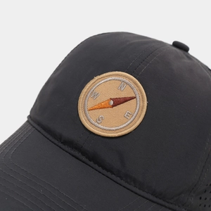 Detail of outdoor baseball cap with embroidered compass patch and premium mesh texture