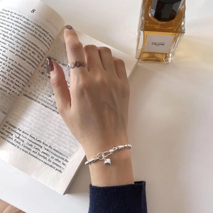 Detail of 925 sterling silver beaded heart bracelet and ring on a vintage book page