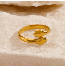 Close-up of gold double-headed snake open ring on white stone base