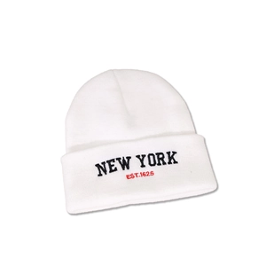 Detailed close-up of white knit beanie featuring black NEW YORK embroidery and red text