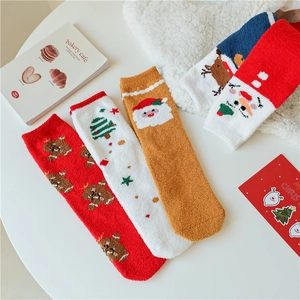 Détail de chaussettes de Noël en polaire corail avec motifs élan et Père Noël en décor d'hiver