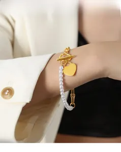 Detail of 18K gold heart pendant bracelet with white pearls and asymmetrical OT clasp