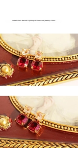 Detail of vintage gold-plated earrings with square red gemstone and white zircon stones