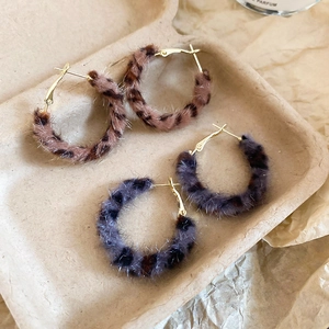 Detail of leopard print faux fur hoop earrings in brown and grey with golden clasps