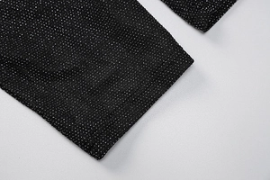 Macro detail of black knit fabric with silver glitter finish and seamless sewing edge