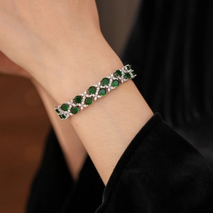 Detail eines zweilagigen Zirkon-Blumenarmbands mit grünen Steinen am Handgelenk