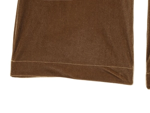 Détail de la texture du velours marron et des coutures lisses sur l'ourlet du pantalon évasé