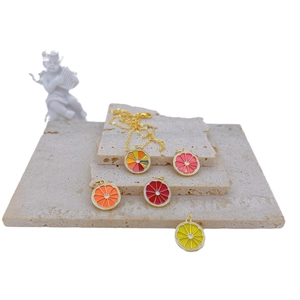 Colorful fruit slice pendants with gold chain on stone tiles in a fresh summer style