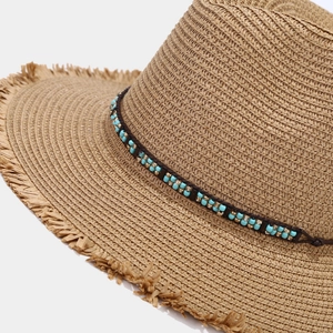 Détail d'un chapeau de paille bohème avec perles turquoise et bord effiloché