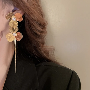 Gros plan de boucles d'oreilles fleurs dorées avec de longs pompons et des zircons brillants