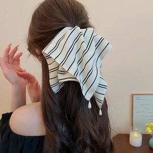 Détail d'une pince à cheveux à nœud rayé avec perles portée dans une coiffure élégante