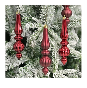 Three red teardrop ornaments hanging on frosted Christmas tree branches with bokeh background
