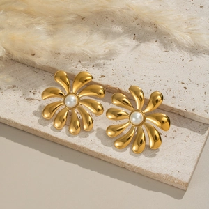 Detail of 18K gold-plated flower stud earrings with central pearl on stone background