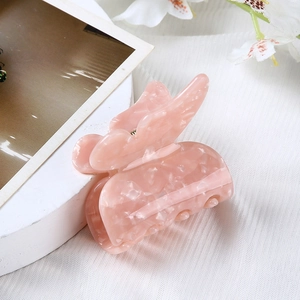 Detailed close-up of a pink marble texture butterfly hair claw clip on white fabric
