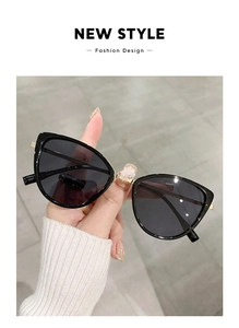 Detailed close-up of retro cat-eye sunglasses with black frame and golden metal accents