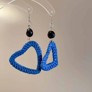 Close-up of blue woven heart earrings with black bead stud and silver hooks