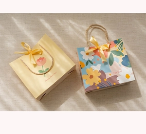 Close-up of premium paper gift bags with ribbons and floral patterns on linen background