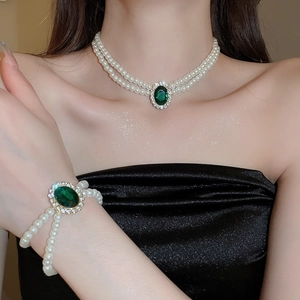 Detailed view of luxury double-layer pearl necklace with emerald green oval pendant