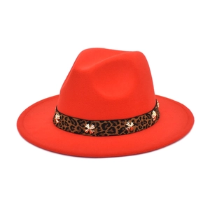 Detail of red fedora hat featuring leopard print band with gold cross rivets