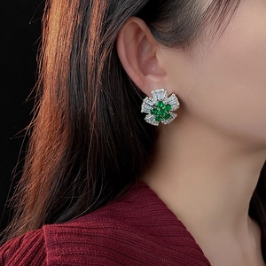 Close-up of sparkling green gemstone flower earrings with white zircon accents on ear
