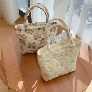 Sacs cabas matelassés à motifs ours et fleurs sur une table en bois ensoleillée